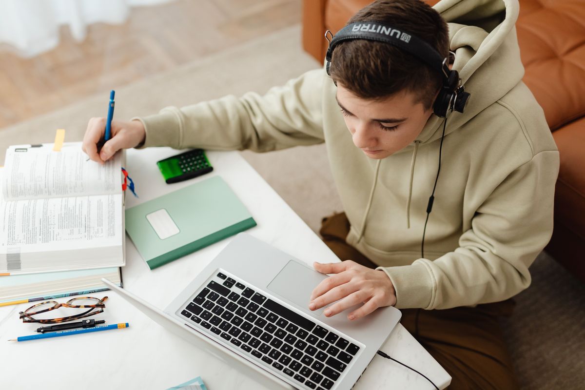 GCSE student revising with a laptop, headphones and notes